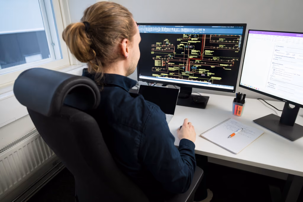 Designer examining a system diagram on two screens