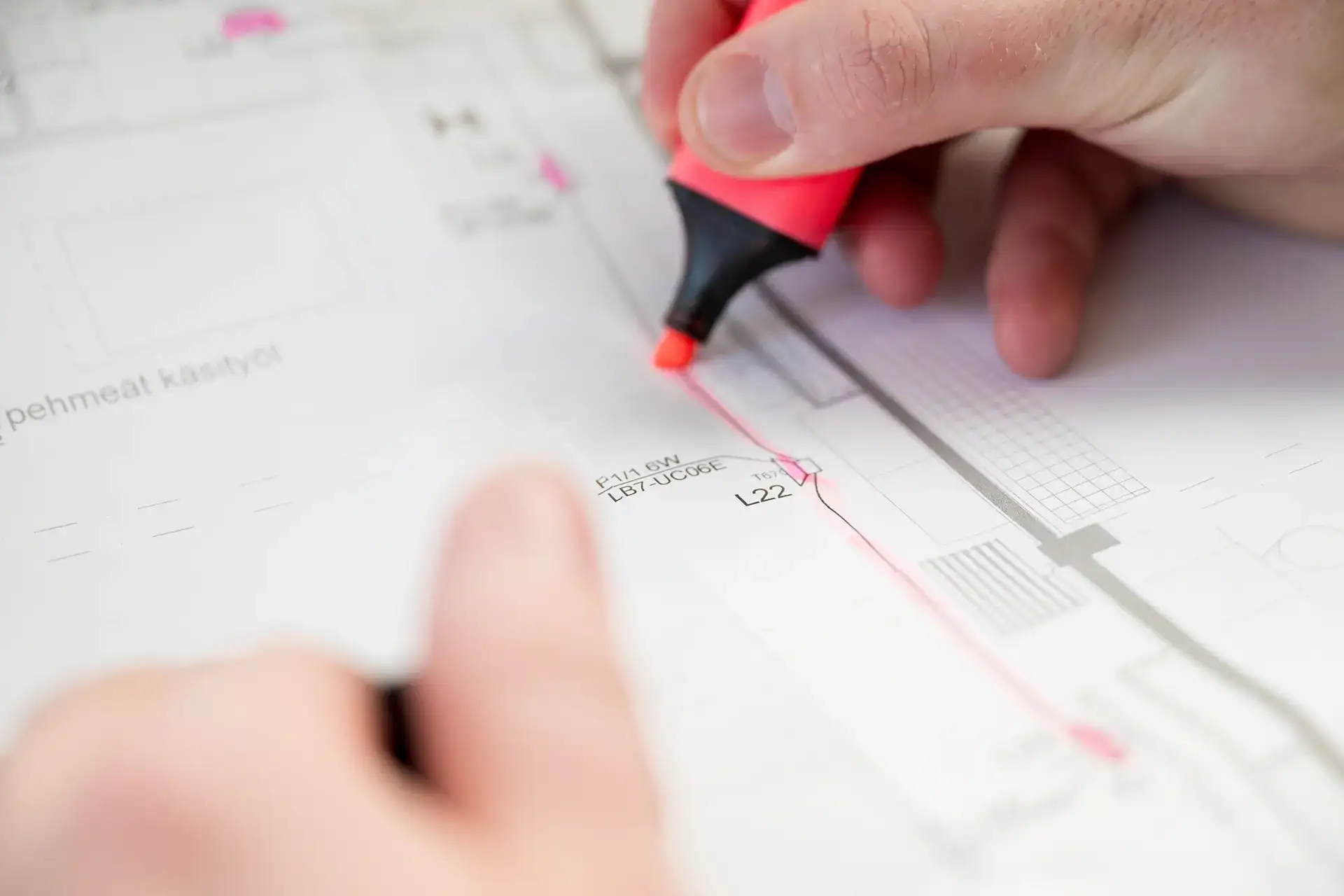 A designer marks details on a building floor plan with a highlighter