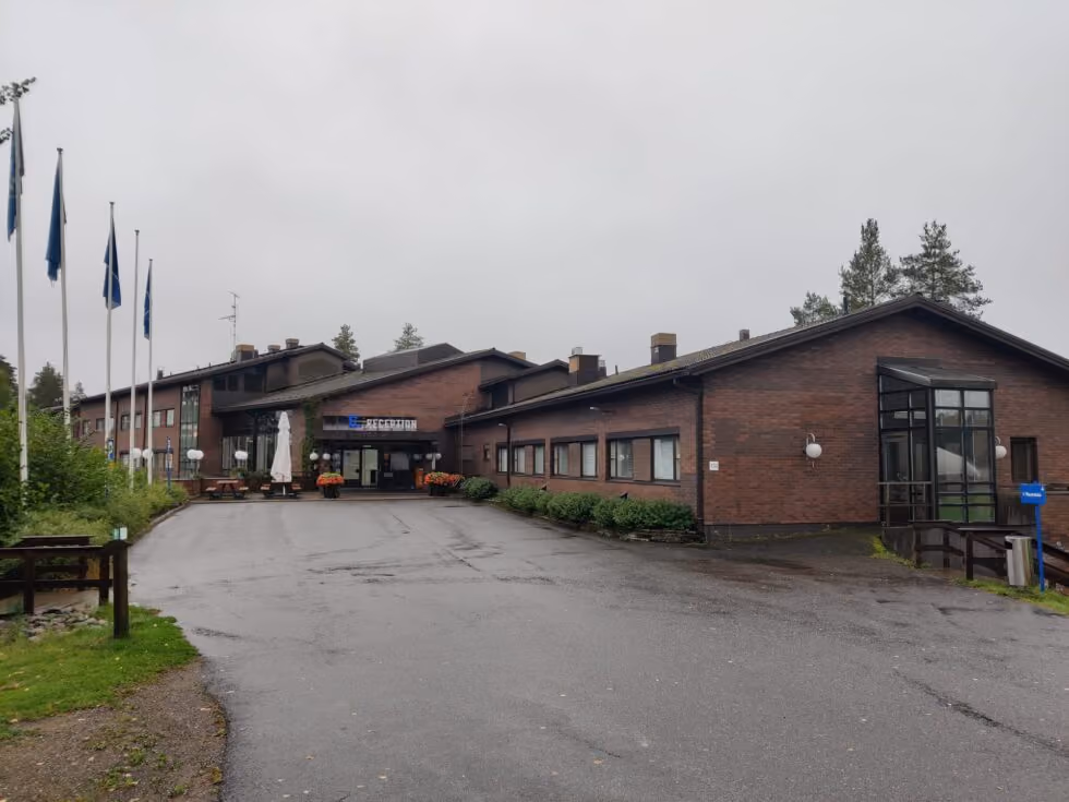 Urheiluopiston punatiilinen päärakennus ja lipputangot sateisena päivänä