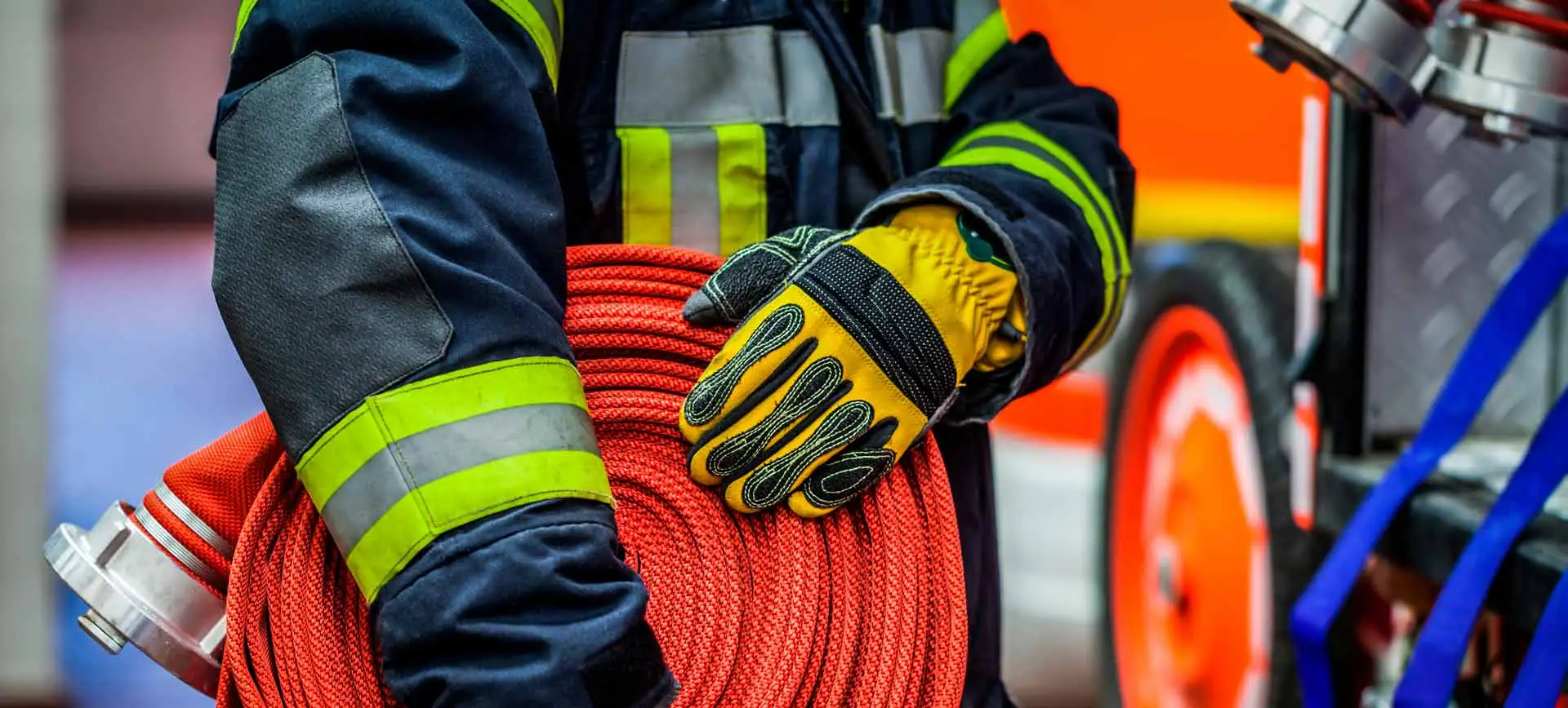 A firefighter carrying a fire hose next to a fire engine