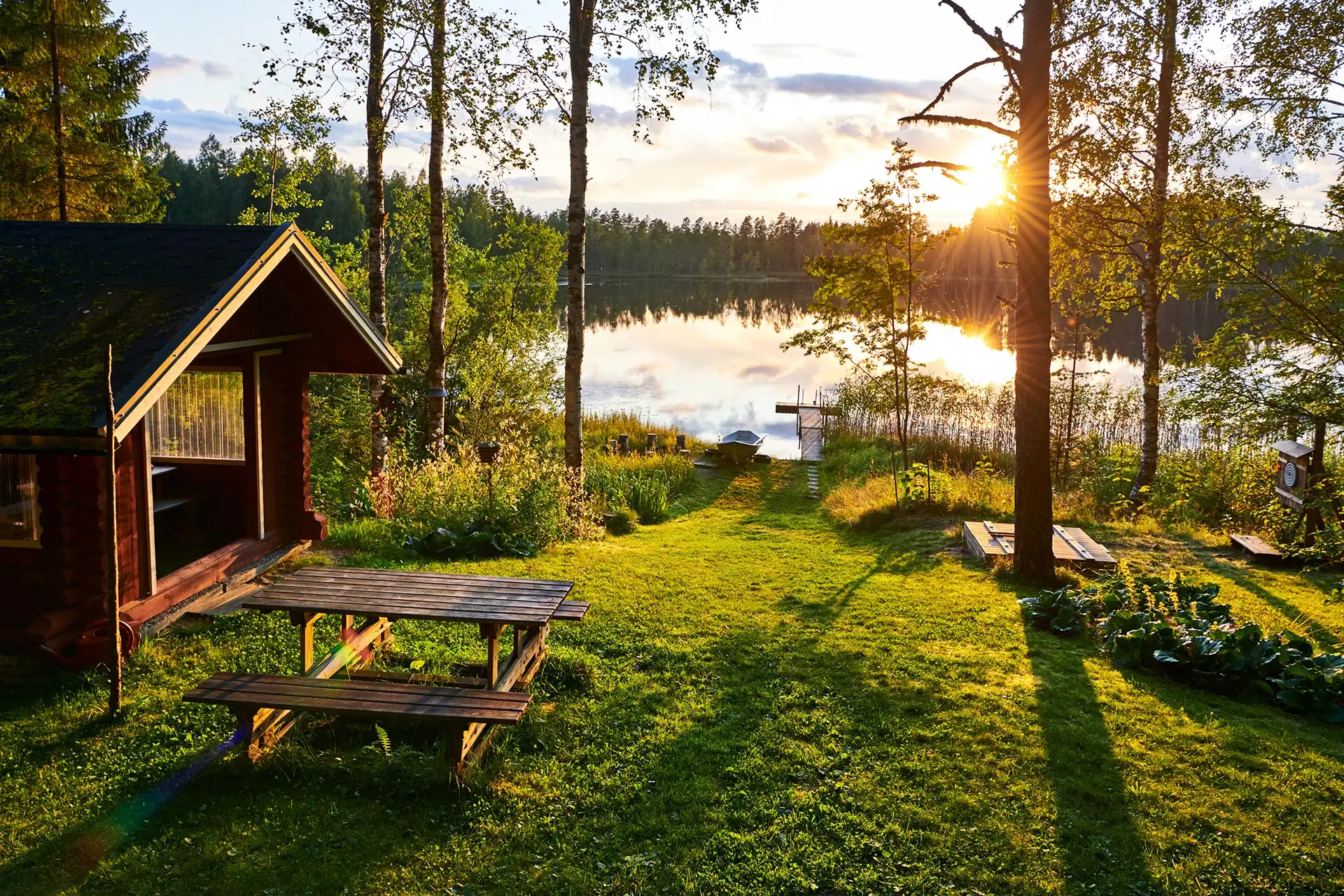 A cottage barbecue shelter and lakeshore in the evening sun