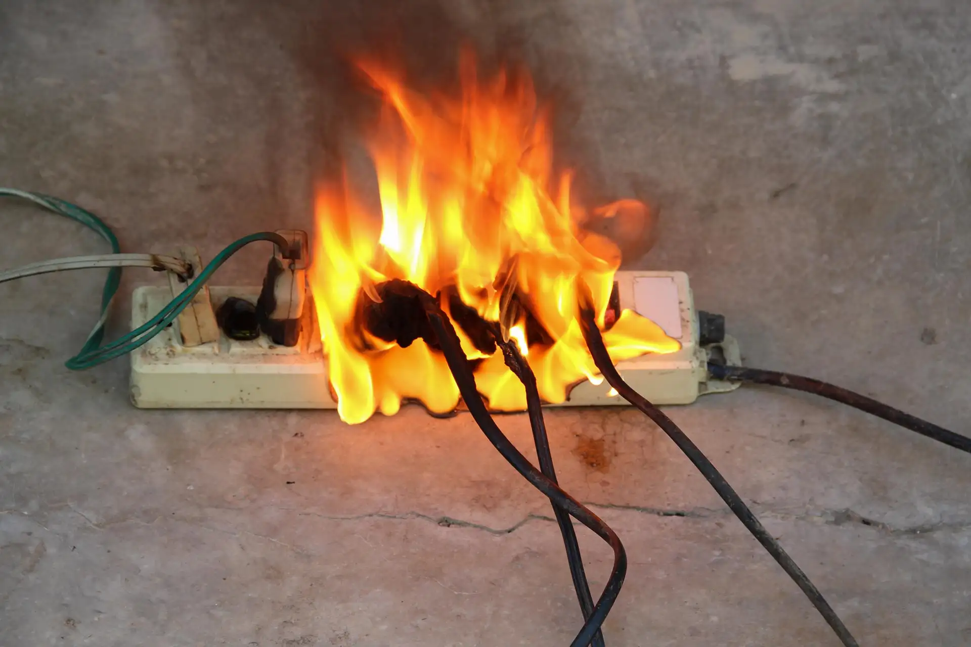 An extension lead and its plugs burning on the floor